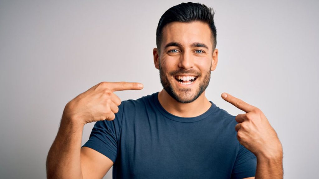 Man Smiling And Pointing At Teeth