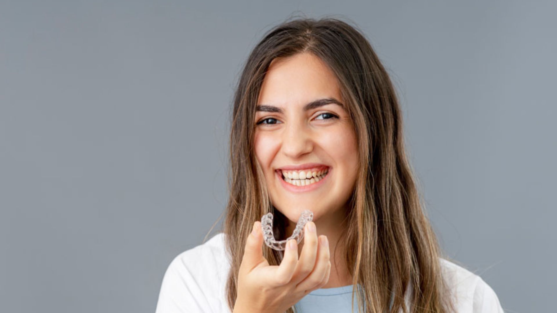 Smiling Woman Holding A Clear Invisalign